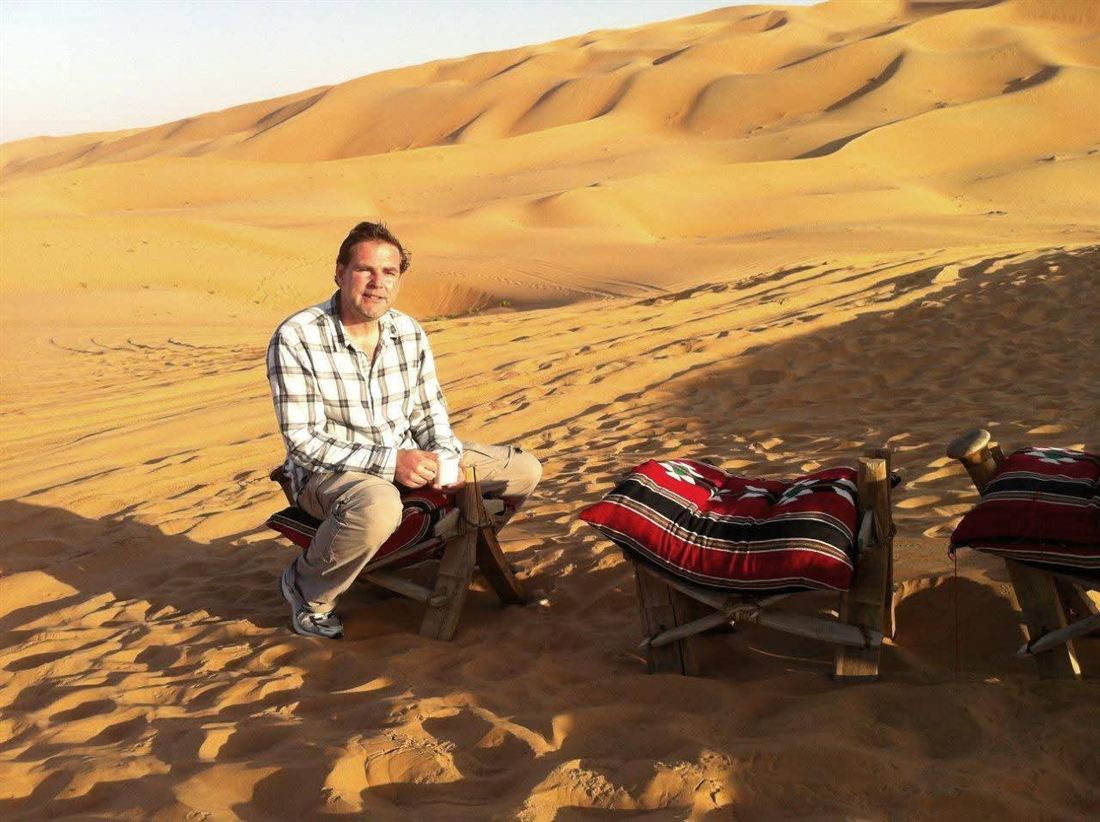 Yves met een kop koffie tussen de zandduinen